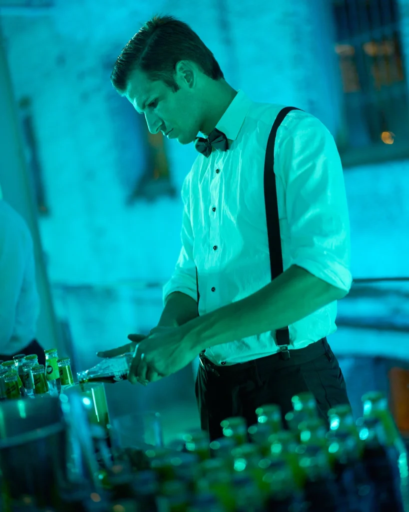 Bartender con tirantes preparando cóctel en evento