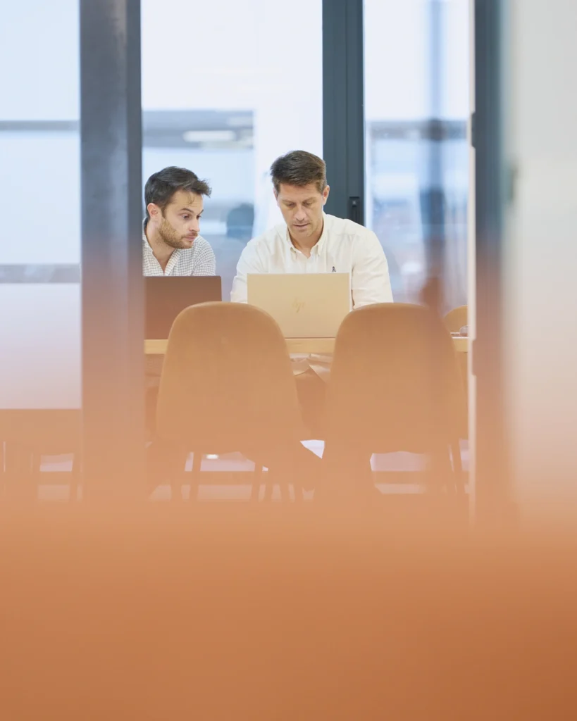 Dos hombres trabajando con laptop en sala de reuniones - Corporate Frame Madrid