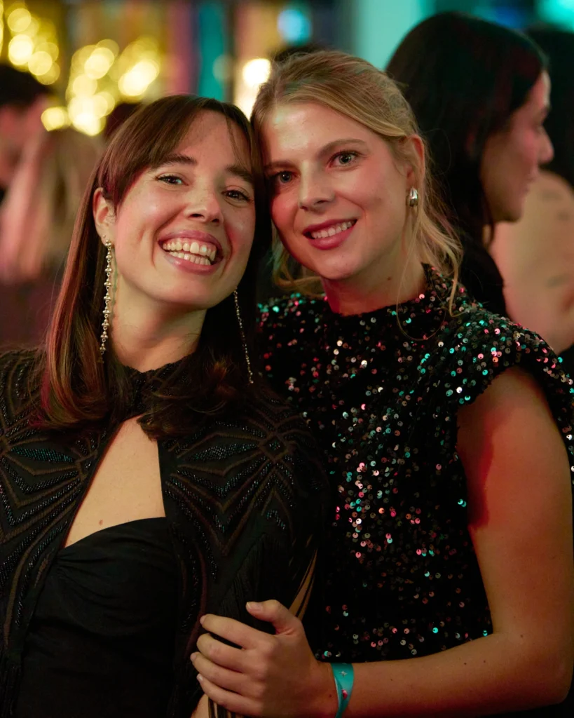 Dos mujeres con vestido de gala sonriendo en evento