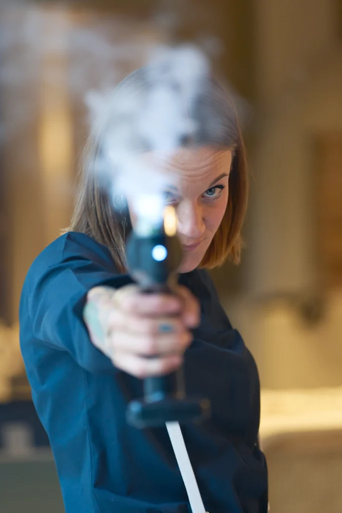 Mujer disparando pistola con humo en actividad de evento