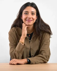 Retrato de mujer con chaqueta oliva apoyada en escritorio