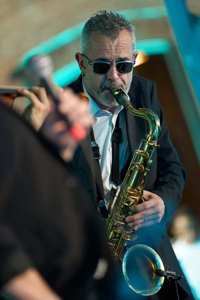 Saxofonista con gafas de sol tocando en evento nocturno