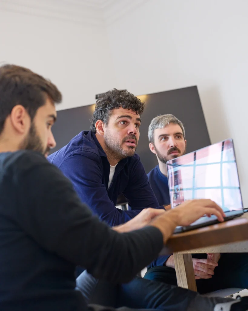 Tres hombres con laptop en reunión informal